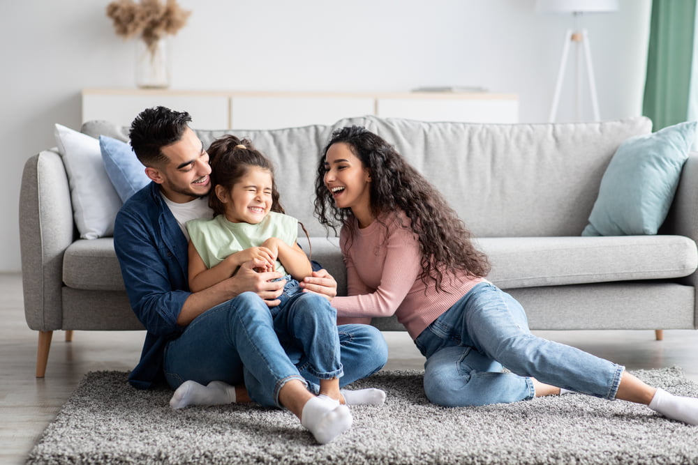 Happy family with parents and child sitting together at home.