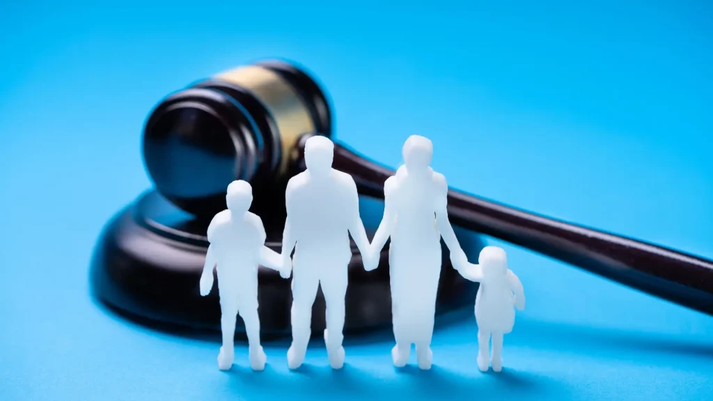 White silhouette figures of a family holding hands in front of a judge's gavel on a blue background.