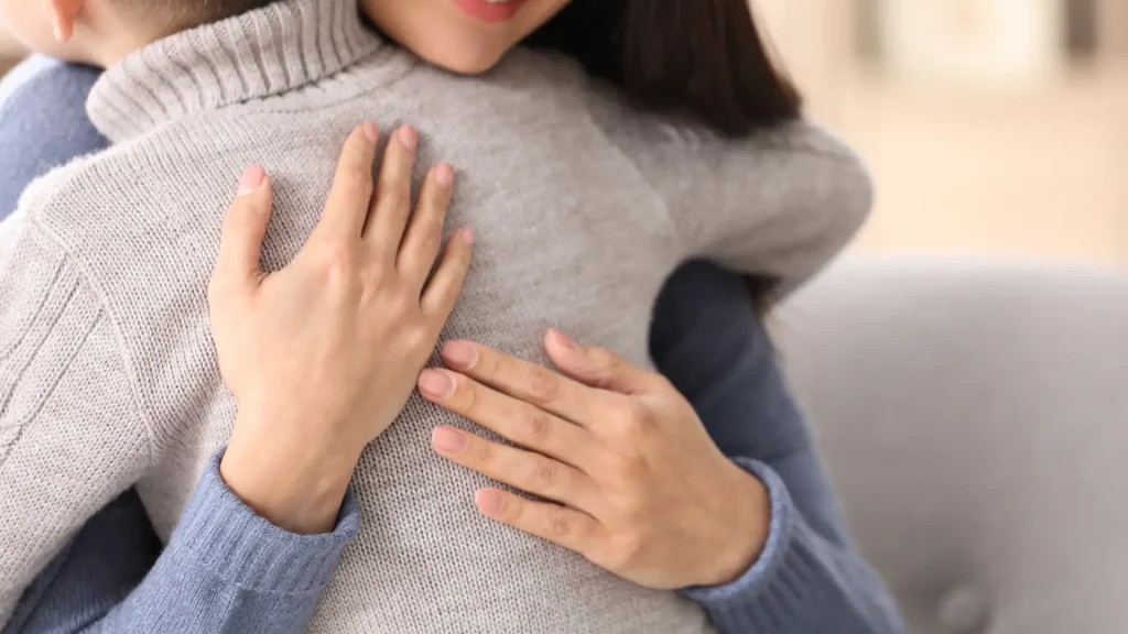 A mother lovingly hugs her child in a sweater, representing the emotional aspects of modifying custody agreements in San Antonio, Texas.