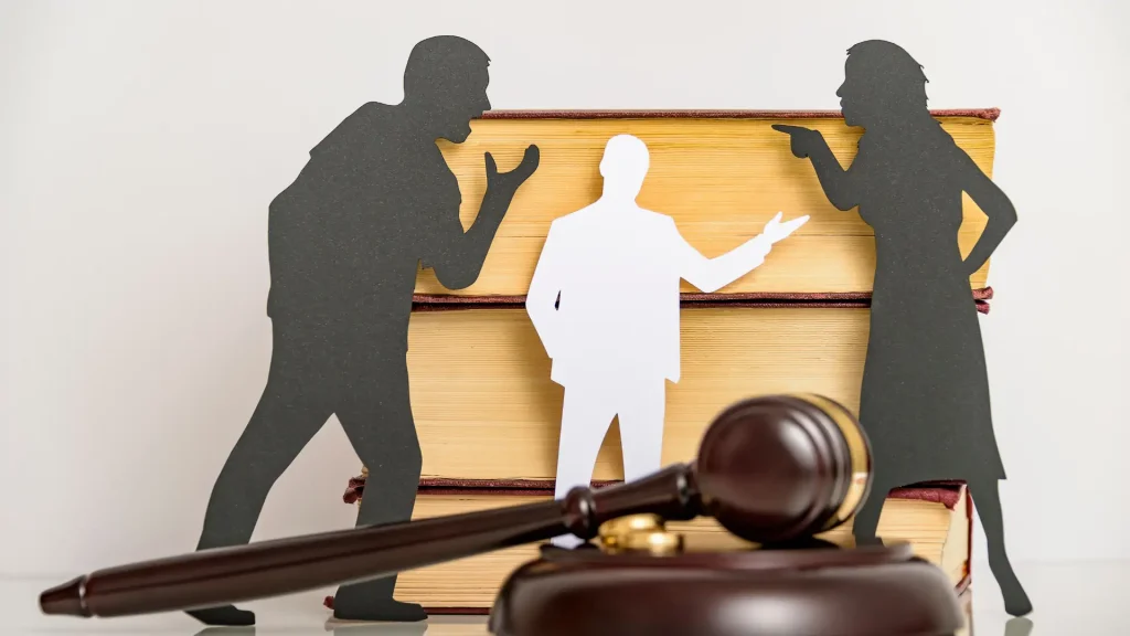 Silhouettes of people in conflict with a gavel and law books in the background.