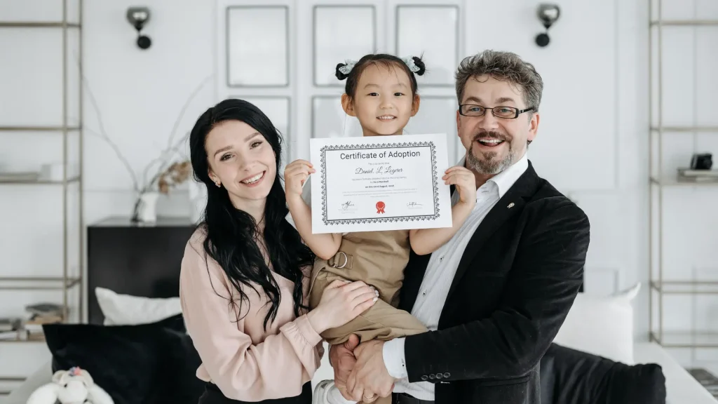 Smiling family holding child with a certificate